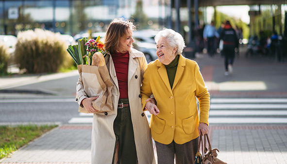 Woman holding groceries walking with senior woman