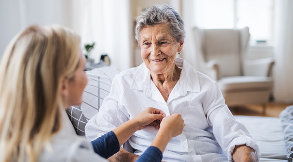 Senior woman being helped dressed by carer