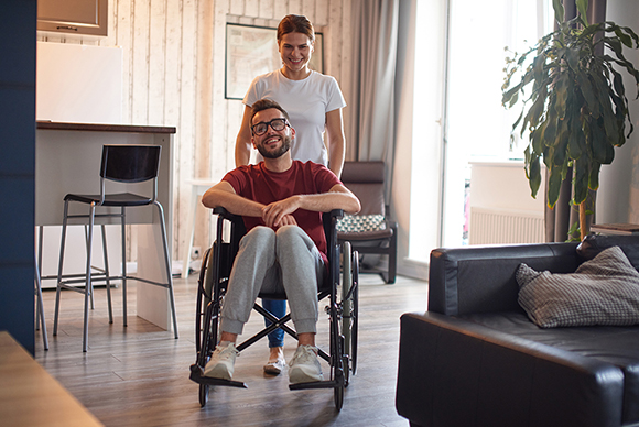 Woman moving man in wheelchair indoors