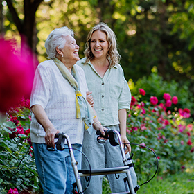 Senior woman with carer walking outside