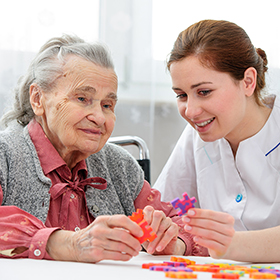 Woman with dementia being helped by carer