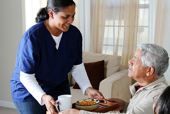 Woman bringing breakfast to senior man