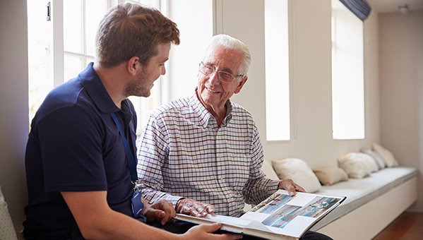 a man talking with a elderly man while reading a book together