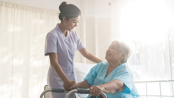 a nurse looking after an elderly lady sitting on a hospital bed